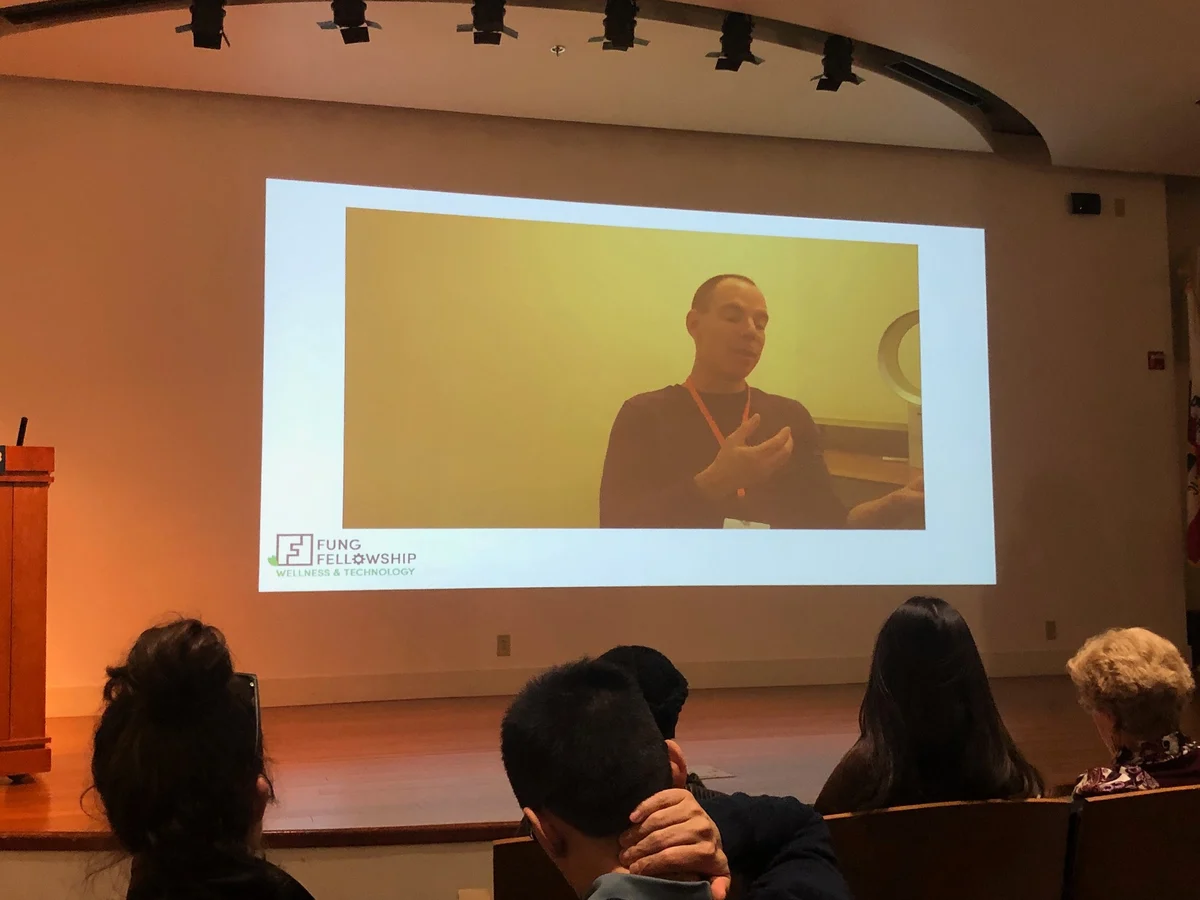 An audience watching Robert Sarison on a conference presentation screen